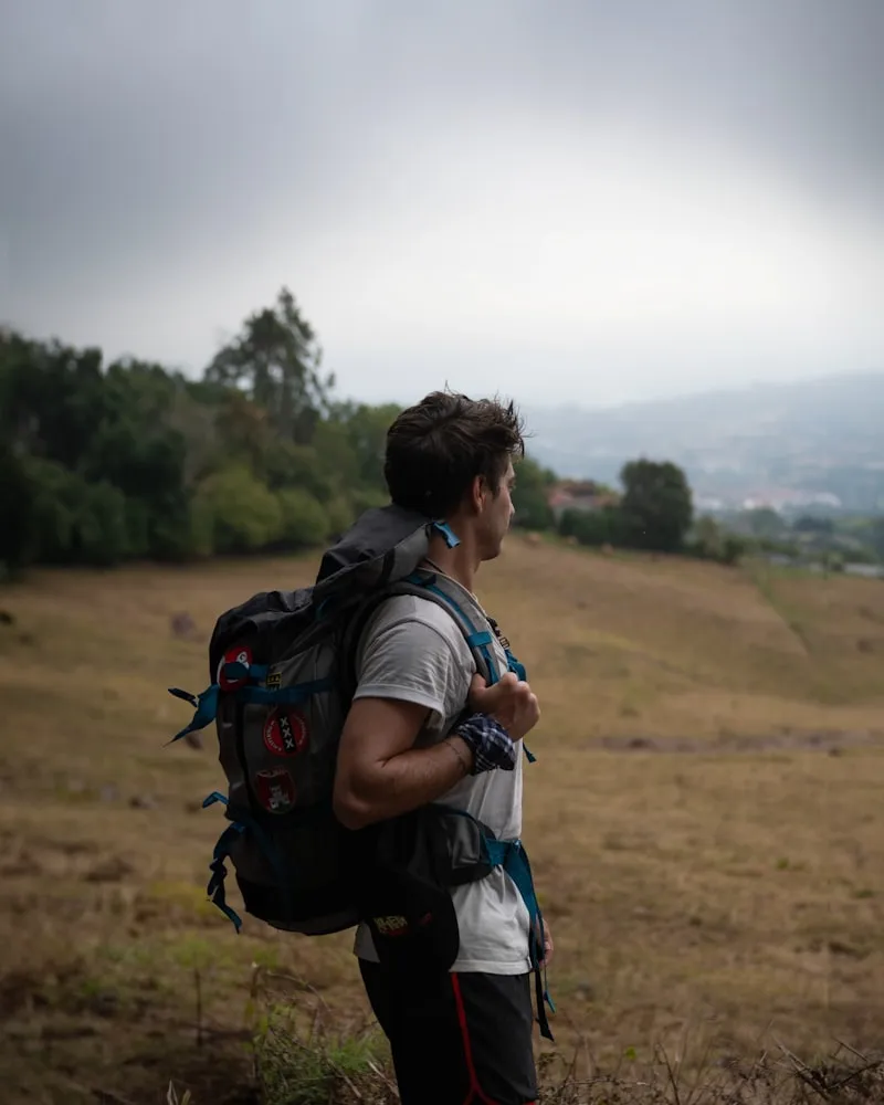 Peregrino con mochila caminando por un campo en el Camino del Norte